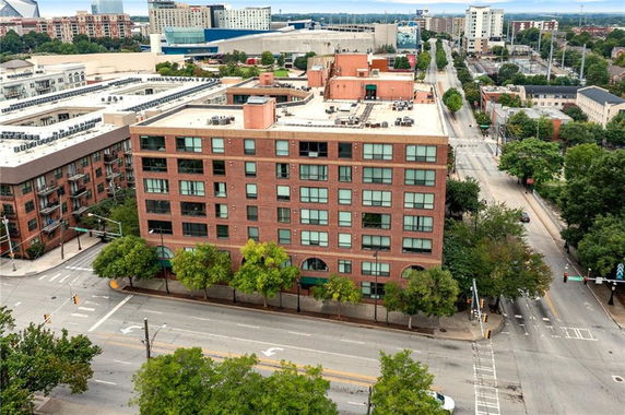 Front view of a multi-story red brick building on a street corner.