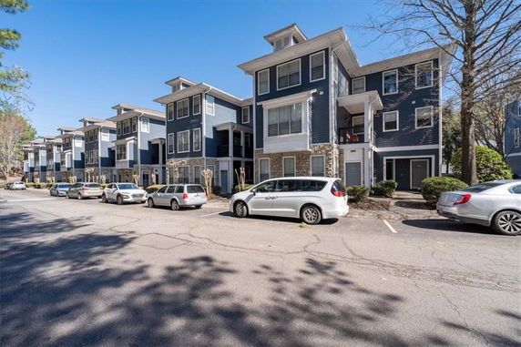 Front view of townhouses with multiple stories and parking area in front.