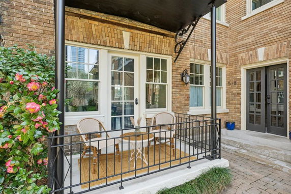 Front view of a brick house with a small porch and patio chairs.