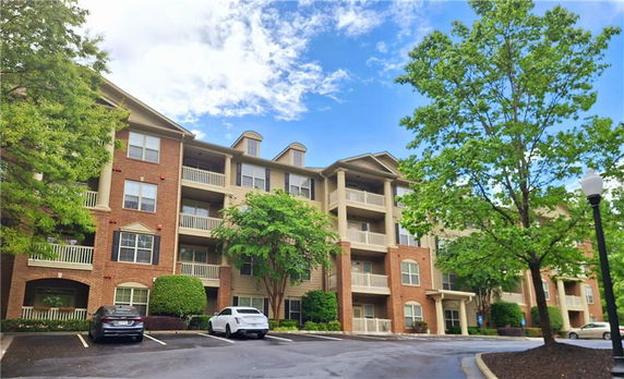 Front view of a multi-story apartment building with brick facade and balconies.