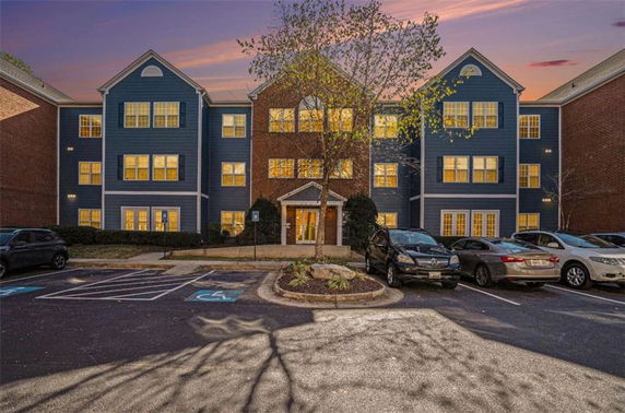 Front view of a three-story building with a central entrance and parking area.