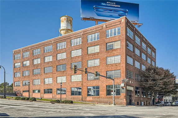 Front view of a multi-story brick building with a water tower on top.