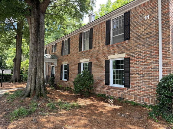Front view of a two-story brick house with black shutters and several windows.
