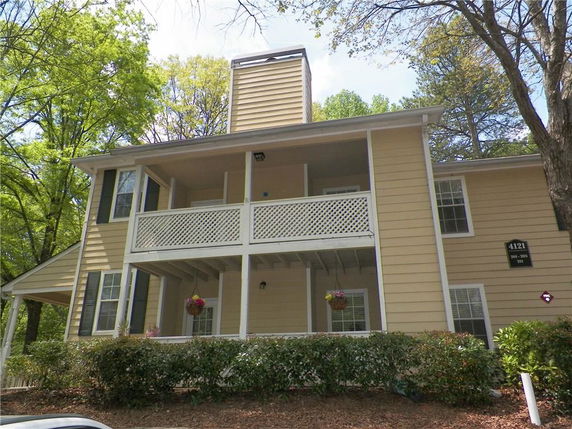 Front view of a two-story house with a balcony and yellow siding.