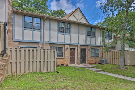 Front view of a two-story townhouse with a fenced yard.