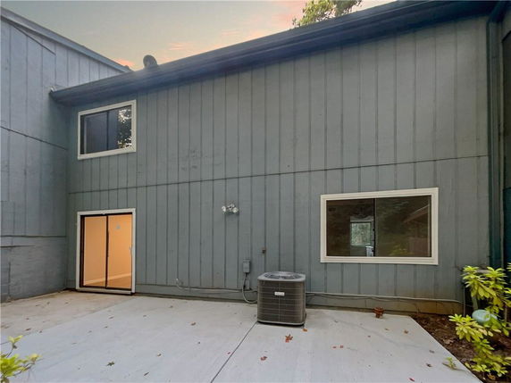 Rear view of a two-story building with sliding glass doors and windows, featuring an outdoor HVAC unit.