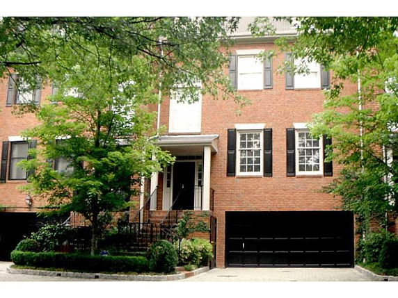 Front view of a multi-story brick house with black shutters and a double garage.