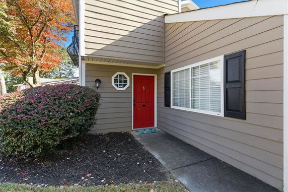 Front view of a house with a red door and beige siding.