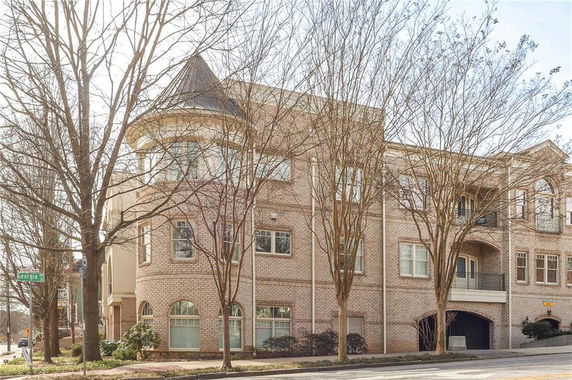 Front view of a multi-story brick building with large windows and a rounded turret.