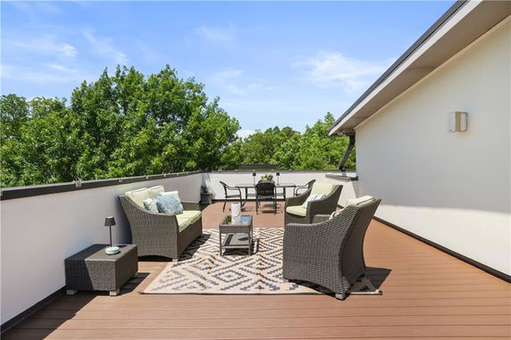 Rooftop patio with seating area and decorative rug.