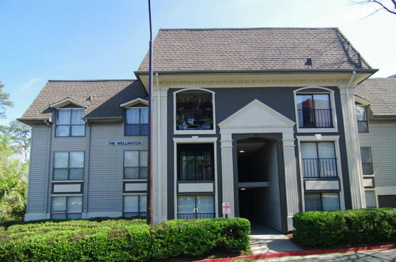 Front view of a multi-story building with a gable roof and an entrance flanked by columns.