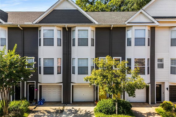 Front view of multi-story townhouse with garages and bay windows.