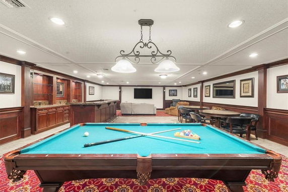 Room featuring a pool table, seating area, and wood-paneled walls.