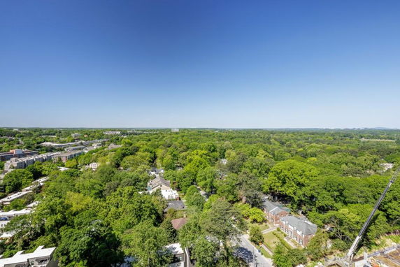Panoramic view of a landscape with trees and buildings under a clear blue sky.
