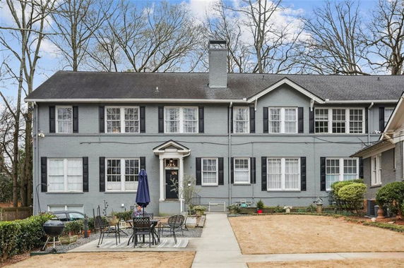 Front view of a two-story house with a central chimney and outdoor seating area.