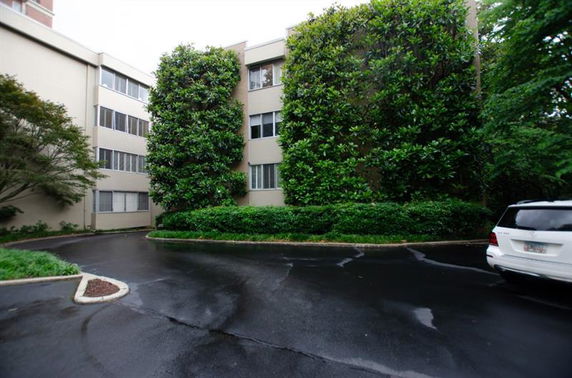 Front view of a multi-story building with large plants on the facade.