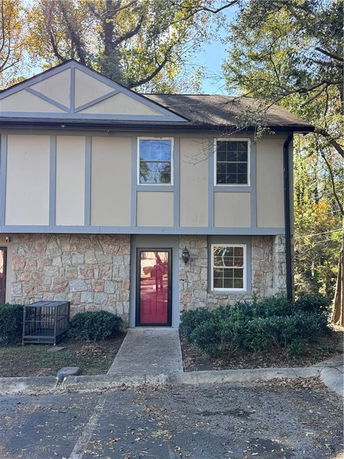 Front view of a two-story house with stone facade on the lower level and beige siding with gray trim on the upper level.