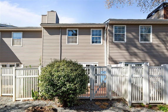 Front view of a two-story house with a white fence.