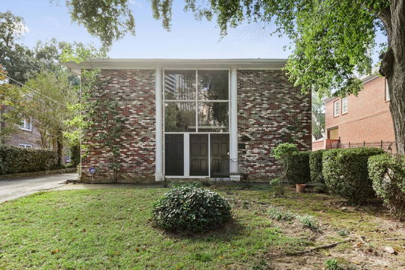 Front view of a two-story brick house with large windows and double doors.