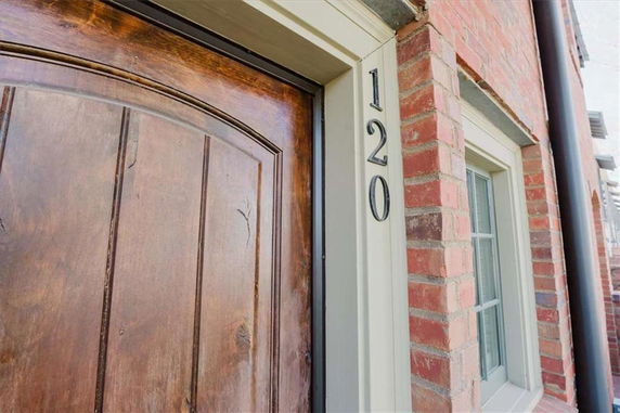 Front view of a brick house with a wooden door and a window next to it.