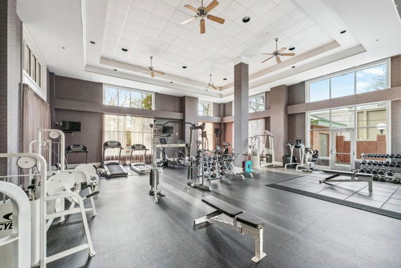 Indoor gym area with various exercise equipment and windows letting in natural light.