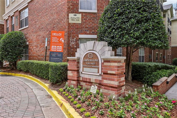 Front view of a brick condominium building with a Cornerstone Village sign.