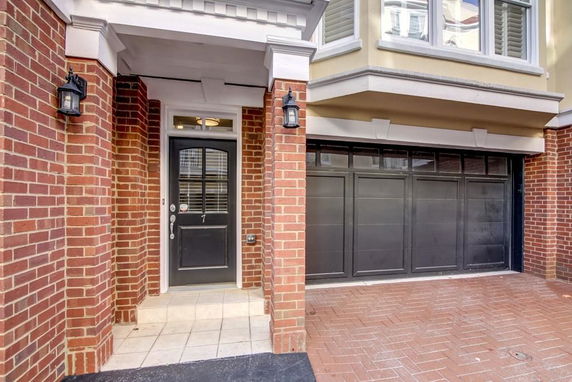 Front view of a house with a brick exterior and a black garage door.