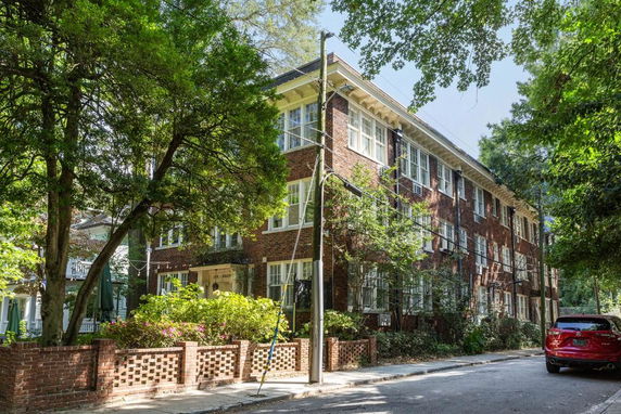 Front view of a multi-story brick building with white-framed windows.