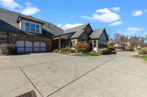 Front view of a multi-story house with a large driveway and a double garage.
