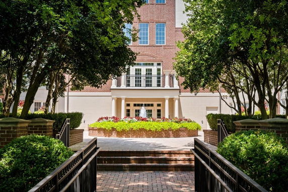 Front view of a building with trees and a landscaped entryway.