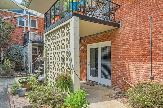 Front view of a brick building with a balcony and decorative lattice wall.