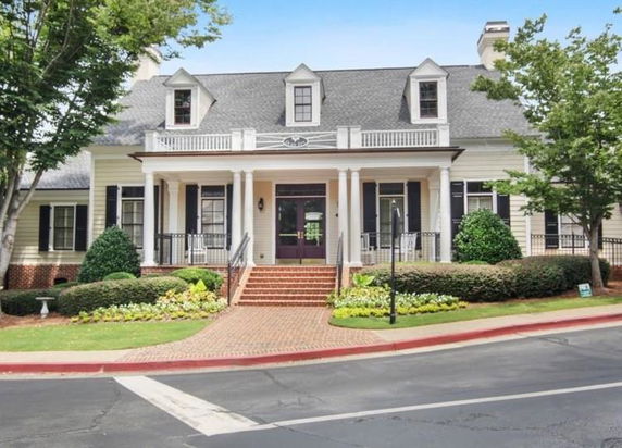 Front view of a house with a large porch and multiple dormer windows.