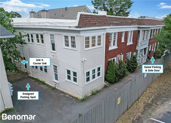 Side view of a two-story building with a corner unit labeled Unit 4, showcasing an assigned parking spot and a gated parking & side door.