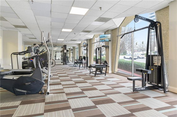 Indoor gym area with various exercise equipment and large windows.