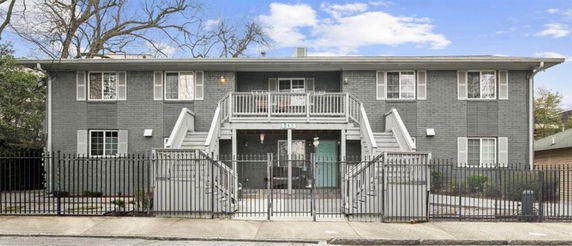 Front view of a two-story building with external staircases and a gated entrance.