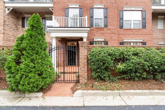 Front view of a brick townhouse with a gated entrance and balcony.