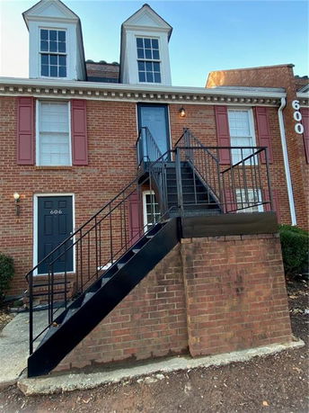 Front view of a brick two-story building with staircase entrance.