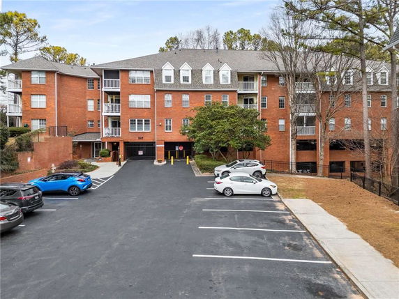Front view of a multi-story brick apartment building with parking lot.