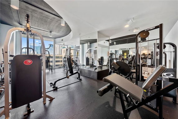 Indoor gym area with various exercise equipment and large mirrors.