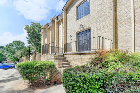 Front view of a brick building with black doors and steps leading up to it.
