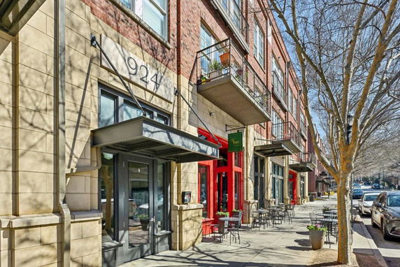 Front view of a multi-story building with balconies and outdoor seating areas.