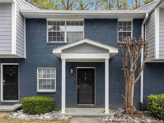 Front view of a two-story townhouse with a brick exterior and a covered entryway.