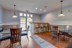 Room with small tables and chairs, featuring pendant lights, wooden flooring, and a counter with high chairs.
