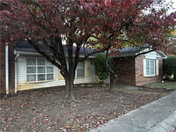 Front view of a single-story house with a tree and a brick facade.