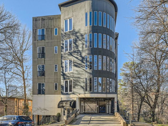 Front view of a modern multi-story building with curved facade and tall windows.