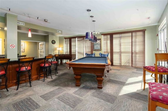 Interior view of a recreation area with a billiards table and bar seating.