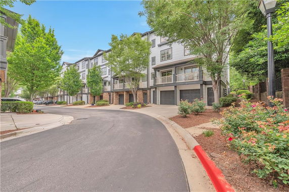 Front view of a multi-story townhouse complex with garage spaces on the ground floor.