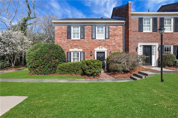 Front view of a brick two-story house with white shutters.