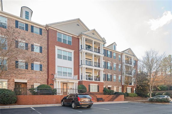 Front view of a multi-story brick apartment building with balconies.