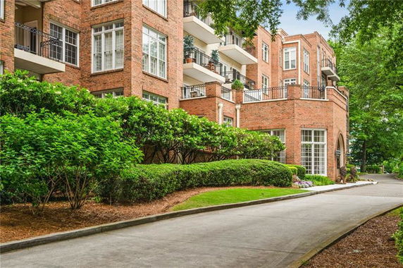 Front view of a multi-story brick apartment building with balconies and large windows.